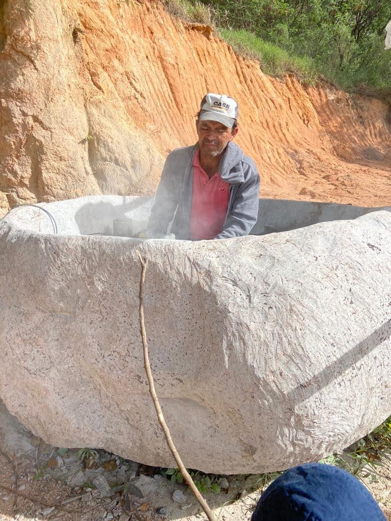 Artesão esculpindo canoa de pedra em bloco de granito